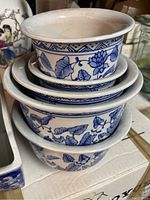 Stack of three round white glass bowls decorated with blue floral designs and geometric border patterns.