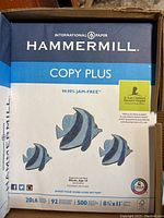 Close-up of one ream of Hammermill Copy Plus printer paper showing product details including 20 lb weight, 92 brightness, 500 sheets, and 8.5 x 11 inches size.
