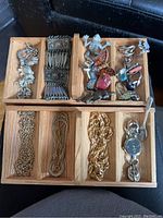 Full top view of all jewelry items placed in wooden compartments showing pins, bracelets, rings, and wristwatch