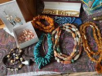 Full view of assorted necklaces, bracelet in box, and earrings displayed on fabric.