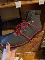 Cole Haan grey leather boot with red laces held in hand