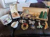 Overview of assorted jewelry items including pins, earrings, necklaces, and bracelet with floral and holiday themes.