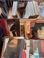 Wooden record box filled with a collection of vinyl record albums showing various genres and artists, some visible album cover art.