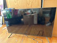 Samsung 55-inch flat-screen TV front view showing screen and angled legs on floor.