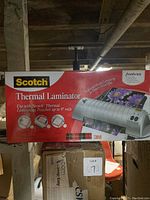 Front of box showing product name Scotch Thermal Laminator and an image of the device with flowers being laminated.