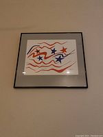 Frontal view of a framed abstract star painting mounted on a wall