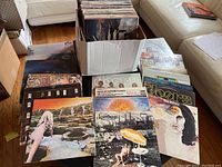 Box of vinyl LP records on table with several albums fanned out