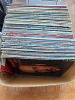 Stack of vintage vinyl records seen from the top, showing many records with worn and aged album covers.