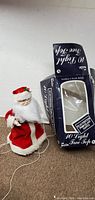 Santa Claus Christmas tree topper dressed in red and white with beard, next to original box with text '10 Light Tree Topper'.