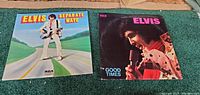 Front covers of the two Elvis Presley LP records 'Separate Ways' and 'Good Times' placed side by side on green carpet.