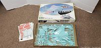 Kit box showing illustration of F-15 Eagle aircraft with included decals and instruction booklet next to plastic sprues.