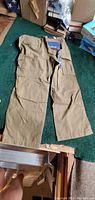 Photo of men's tan cargo pants laid flat showing front side with pockets and tags