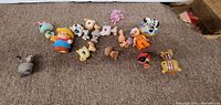 Top-down view of 16 toy figures arranged on carpet showing various animal and human-like characters.