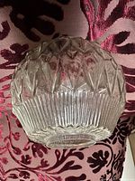 Single clear antique glass lamp shade with geometric ribbed and diamond pattern on a pink fabric background.