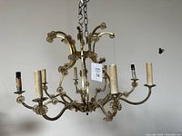 Full view of the antique brass chandelier fixture with multiple arms and floral accents.