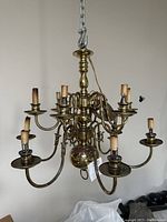Full view of antique brass chandelier showing overall structure, multiple arms, and candle-style bulb holders.