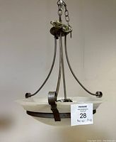 Front angled view of the chandelier showing the frosted glass bowl shade held by a curved metal frame and chain hanging element, with wiring wrapped at top.