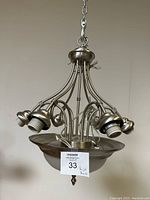Metal hanging chandelier with curved arms and bulb sockets, shown hanging from chain with top ring attachment, neutral background