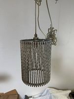 Front view of the chrome hanging light fixture showing cylindrical cage design and central socket.