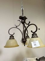 Front view of the three-light fixture showing bronze-colored metal frame and amber glass shades.