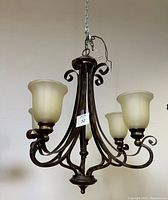 Full view of the vintage five-arm light fixture showing the dark metal finish and curved arms with frosted glass shades.
