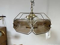 Front angled view of vintage multi-arm light fixture showing brass metal frame and frosted glass shades with embossed patterns and ruffled edges.