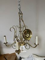 Full view of the vintage brass chandelier showing the five candle-style light holders and hanging chain with ceiling plate.