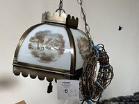 Side view of the hanging light fixture showing metal frame and painted glass panel with winter country scene including snow, horses, and trees.