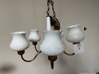 Overall view of the 5-arm light fixture showing brass arms and five hobnail glass shades from a slightly elevated angle.