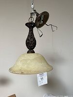 Full view of vintage hanging light fixture with bell-shaped textured glass shade and ornate carved metal