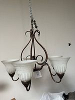 Side view of the 5-light chandelier showing glass shades and curved metal arms.