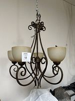 Full view of the vintage light fixture showing metal frame and four glass shades
