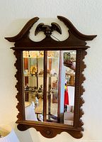 Wall mirror with American eagle carved wooden frame showing reflection from room