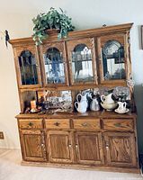 Full view of oak china buffet cabinet displaying glass doors in upper section with decorative patterns and solid oak lower section with drawers and doors. Decorative brass hardware is visible.
