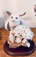 Porcelain owl figurine featuring two adult owls with two owlets on wooden base