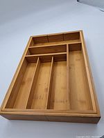 Top view of wooden cutlery drawer insert showing multiple compartments and adjustable dividers.