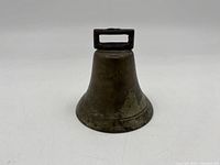 Front side angle of antique cow bell showing flared body and rectangular handle