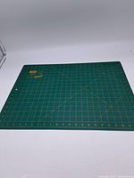 Full view of the green cutting mat showing grid and measurement markings in yellow.
