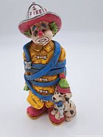 Front view of firefighter clown figurine showing detailed facial features, uniform, and Dalmatian dog.