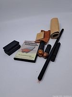 Photo showing entire flint knapping set including DVD, tools, glove, leather roll, and sharpening stones arranged on a white surface.