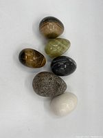 Photo showing all six decorative stone eggs clustered together on a white surface, showcasing size and variety.