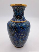 Front view of blue cloisonné vase showing gold wire floral designs on blue enamel.