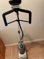 Full view of the Conair clothes steamer showing the built-in hanger and telescoping pole on wheeled base.
