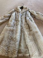 Cream lynx fur coat laid flat showing full length, fur collar/hood, side pockets and satin lining