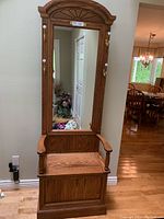 Front view of the solid oak entrance bench showing the large rectangular mirror with a carved arch top, armrests, and seat storage bench below.