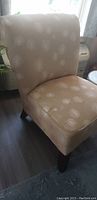Side view of beige patterned slipper chair showing curved back and wooden legs