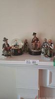 Group photo of six Norman Rockwell style figurines including the music box and five additional nude men characters