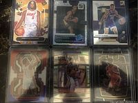 Photo showing six NBA basketball cards including Precious Achiuwa, Davion Mitchell, Keegan Murray, Bones Hyland, and Keon Johnson cards with various holographic and parallel finishes.