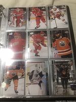 Photo of pages in binder showing hockey cards primarily featuring Detroit Red Wings and Edmonton Oilers players.