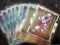 Photo showing Derian Hatcher New York Rangers die cut hockey card with gold Background and prizm finish, plus additional blue and gold parallel cards behind it.